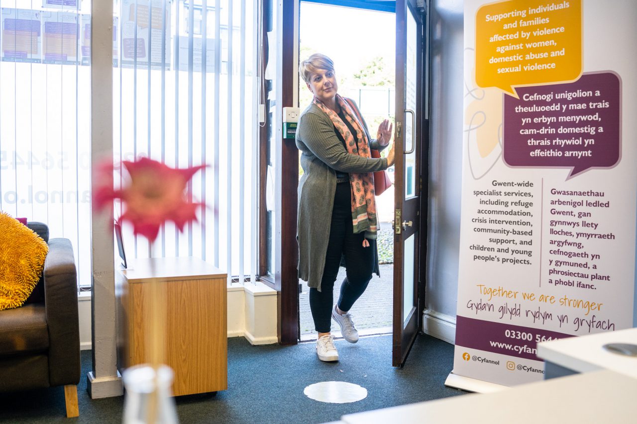 Person walking through a door into a colourful room with yellow and red quotes on the wall.