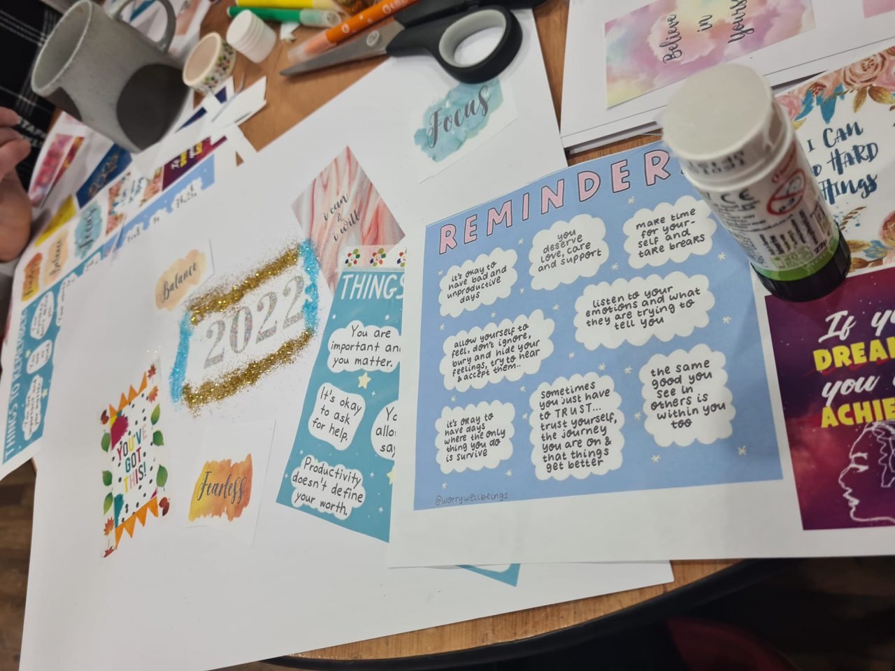 Large white sheet of paper with 2022 written on it. There are colourful sheets of paper scattered on it, with scissors and empty paper cups near its edges.