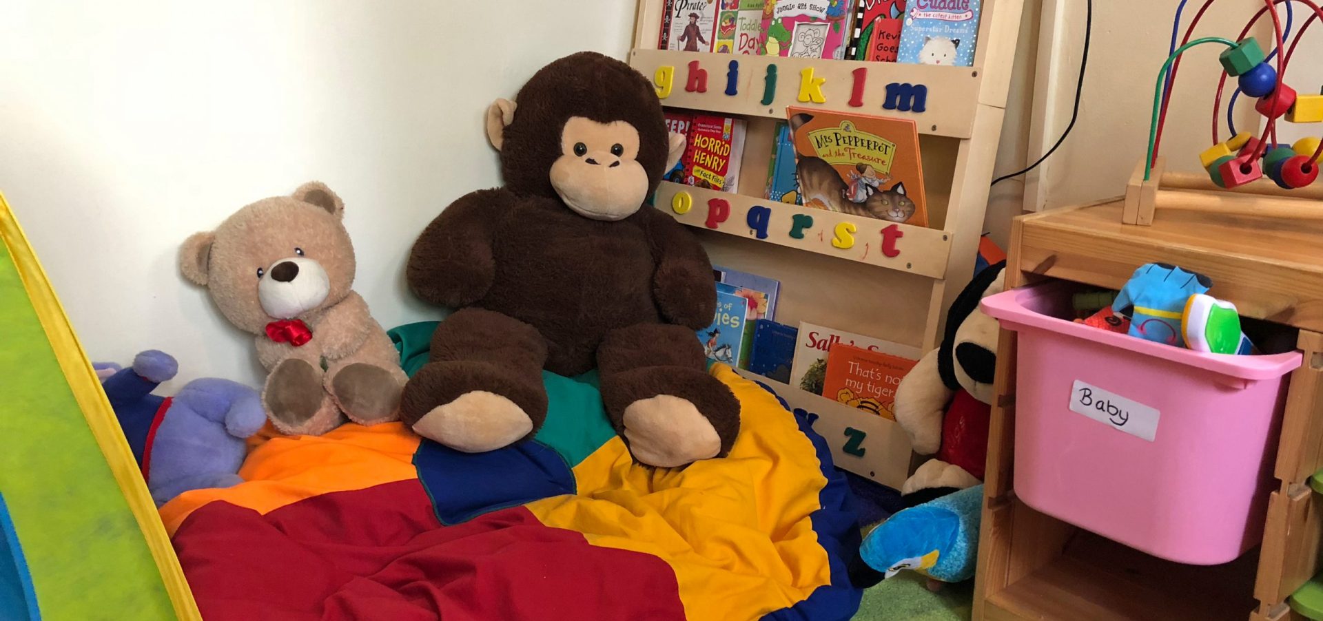 Children's playroom with stuffed animals, blankets and toys scattered throughout.