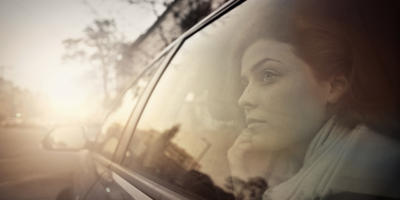 Person with dark hair gazing out the window of a car.
