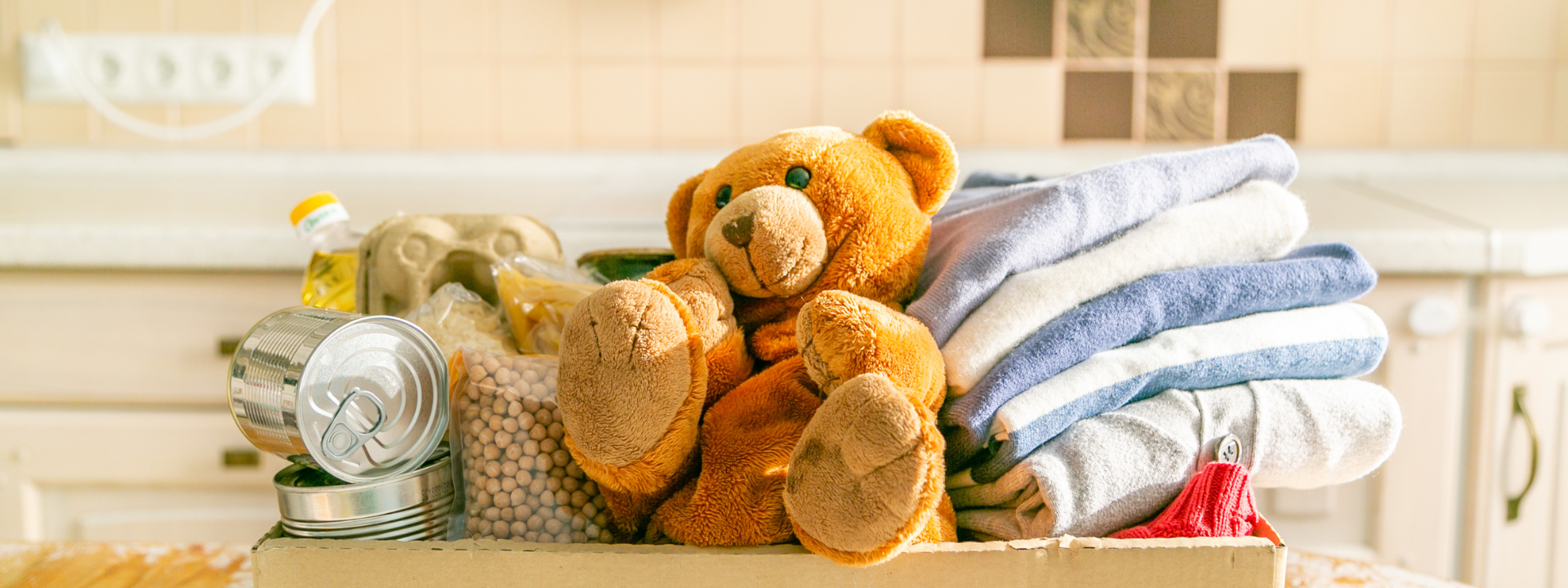 A brown teddy bear nestled in a pile of folded towels.