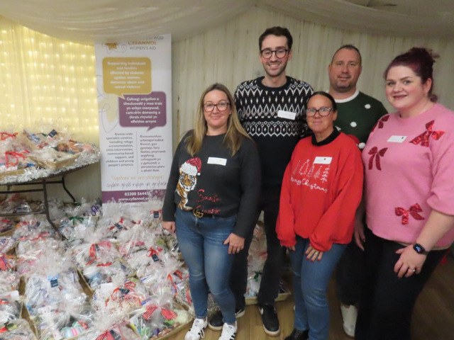 Five people from Propel Finance (two men and three women) standing beside hampers they created while volunteering at Cyfannol’s Hampers of Hope event in 2025.